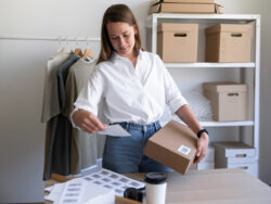 Kobieta pakująca paczkę zwrotną w sklepie internetowym z odzieżą